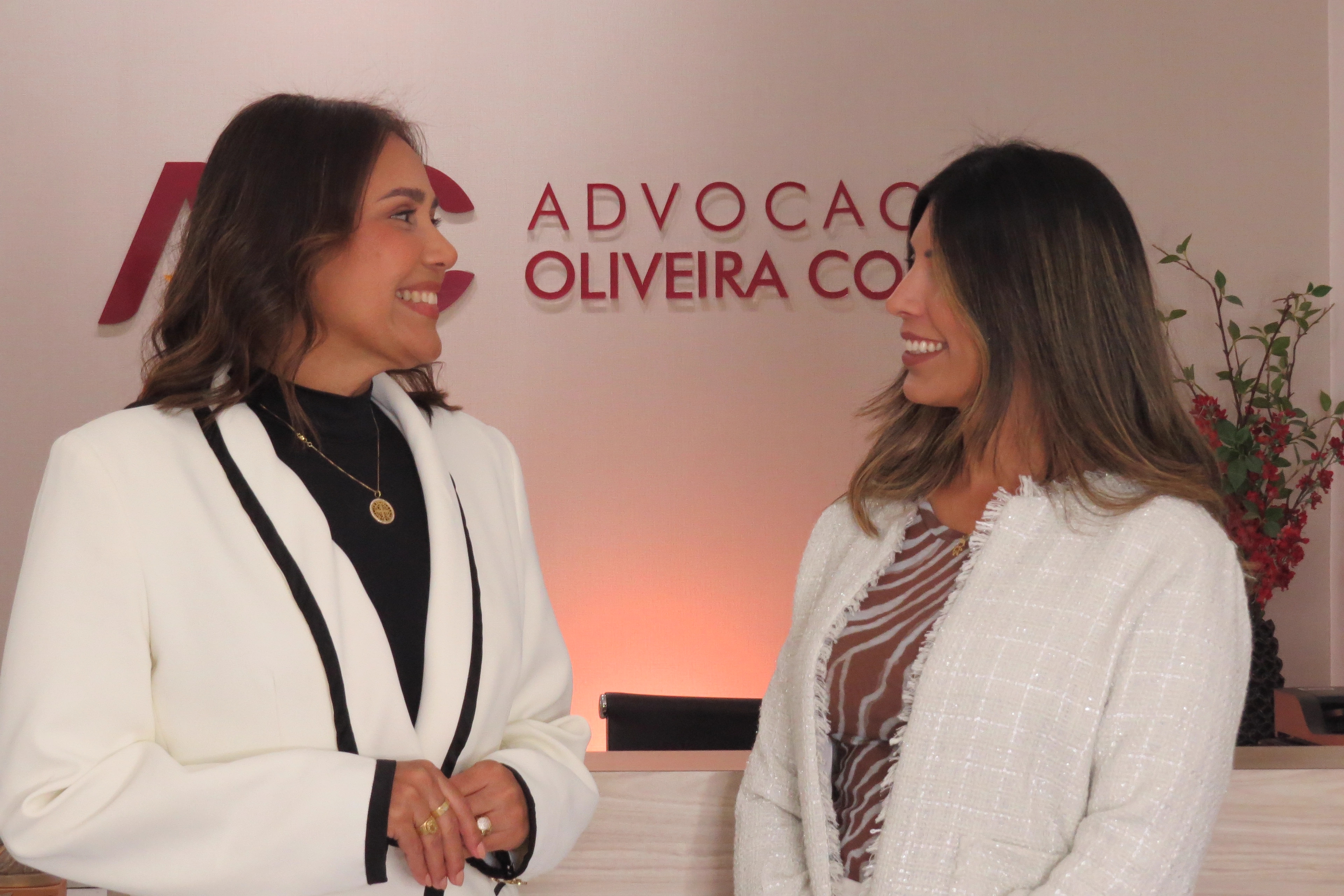 Duas advogadas da Advocacia Oliveira Costa conversando na recepção do escritório